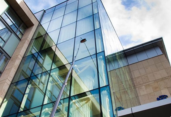 A water-fed pole is cleaning the facade of a glass building