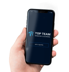 A hand is holding a phone with the company's logo and a Get a Quote button on the screen